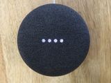 une photo d'une enceinte Google Home noire posée sur une surface en bois