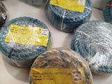 de nombreuses pelotes de laine emballées dans du film alimentaire, posées sur une table