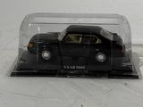 a black toy car in a clear case on a white surface
