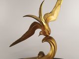 an image of a gold bird statue on a black base
