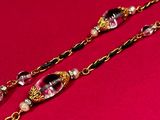 a close up of a pair of long necklaces on a red surface