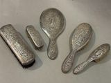 five silver spoons, a brush, and a comb on a table