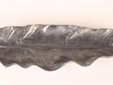 a silver leaf shaped object on a white surface