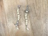 a pair of pearl and silver earrings on a wooden table