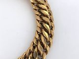 a close up of a gold chain bracelet on a white surface