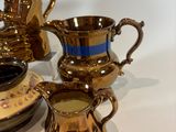 a lot of gold and blue cups and saucers on a table
