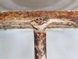 a close up of a rusted metal table with a bowl on it