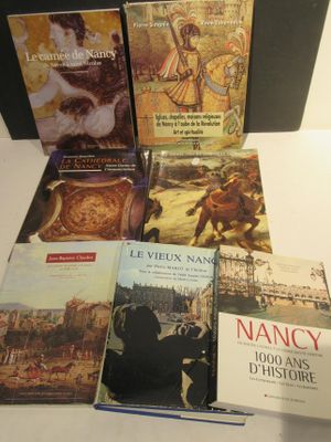Plusieurs livres sont empilés sur une table devant une mallette noire