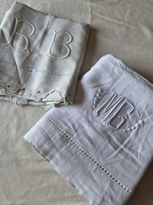 deux serviettes de table ornées de monogrammes brodés, posées sur un lit