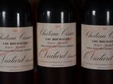 three bottles of red wine are lined up on a shelf