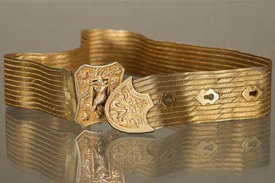une image montrant un gros plan d'une ceinture dorée munie d'une boucle
