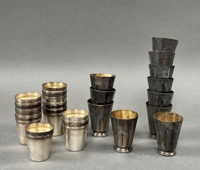 Plusieurs coupes et tasses en argent sont alignées sur une surface grise