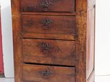 a small wooden chest of drawers next to a red suitcase