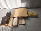 Plusieurs vieux livres sont posés sur une table, à côté d'un rideau blanc.