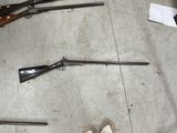 plusieurs armes à feu et une paire de chaussures par terre
