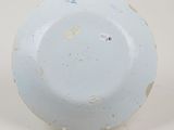underside view of a blue and white plate on a stand