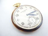 a close up of a pocket watch on a white surface