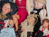many dolls sitting in a basket together on the floor
