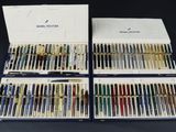 deux jeux de stylos et une boîte de stylos posés sur une table