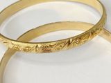 pair of gold tone bangles with engraved design on the sides