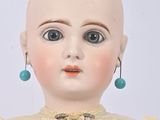 a close up of a doll wearing a dress and earrings