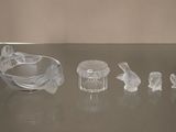 de nombreux animaux en verre posés sur une table, à côté d'un bol