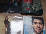 quatre CD posés sur une table, avec un homme en arrière-plan