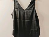 a black top hanging on a wall with a wooden hanger