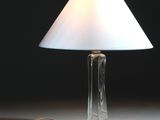 une lampe posée sur une table, avec un abat-jour blanc
