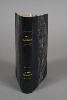 an old book with a black cover sitting on top of a table