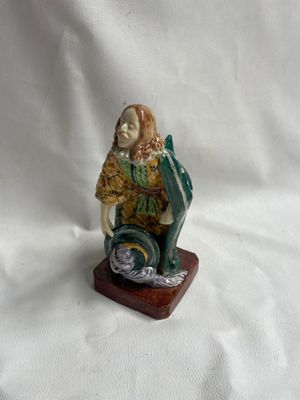 figurine représentant un homme assis sur un bloc de bois