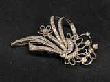 a close up of a silver brooch with diamonds on a black background