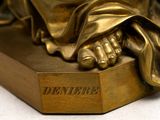 a bronze statue of a person holding a book