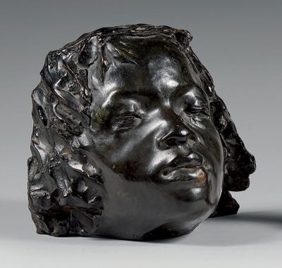 sculpture représentant une tête de femme posée sur une table à côté d'un vase
