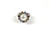 un gros plan d'une bague ornée d'une perle entourée de pierres multicolores