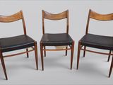trois chaises en bois dont les assises sont recouvertes de cuir noir, sur fond blanc