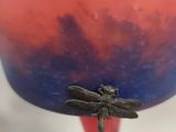 a dragonfly sitting on top of a red vase