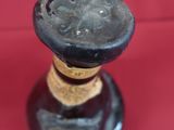 a small glass bottle with a cork stopper on a red surface