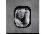 une photo en noir et blanc d'une femme regardant par la fenêtre