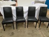 quatre fauteuils en cuir noir sont alignés contre un drap blanc