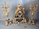 une horloge en or et un ensemble de trois bougeoirs