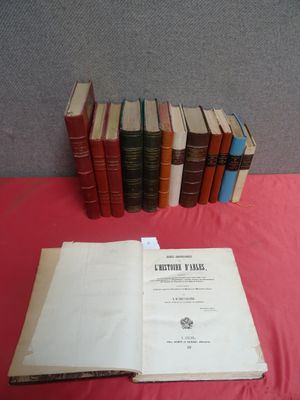 Plusieurs vieux livres sont empilés sur une table recouverte d'une nappe rouge.