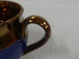 a blue and gold cup sitting on a white surface
