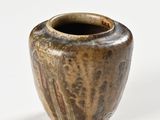 a brown vase that is sitting on a white surface