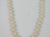 a close up of a pearl necklace on a white surface