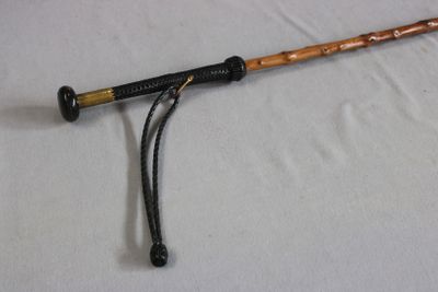 un bâton en bois avec un manche noir sur un fond blanc