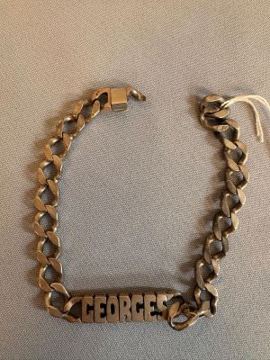 un gros plan sur un bracelet en or sur lequel est gravé le mot « George »