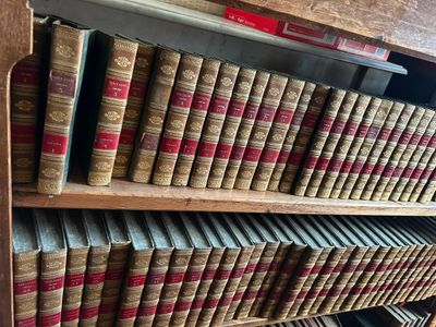 de nombreux livres anciens sur une étagère en bois dans une bibliothèque