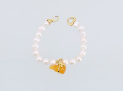 un bracelet de perles blanches orné d'une breloque en forme de papillon doré