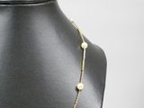 a gold necklace with pearls on a mannequin neck